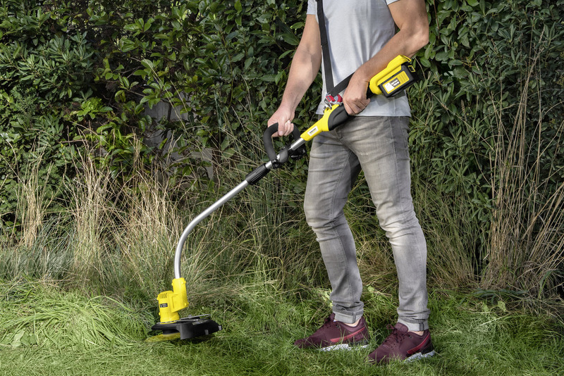 Mann trimmte Gras mit gelbem Akku-Rasentrimmer neben Hecke.