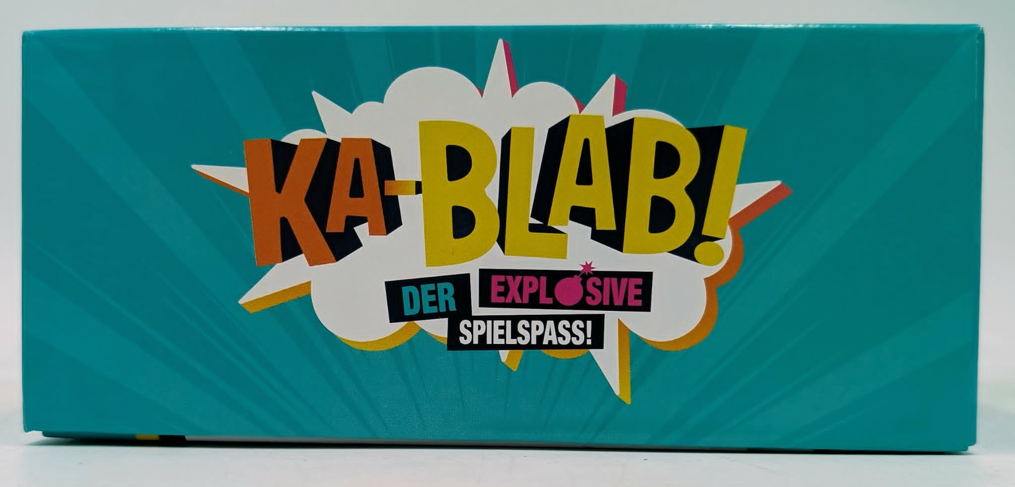 Türkisblaue Box mit dem Text "KA-BLAB! DER EXPLOSIVE SPIELSPASS!"