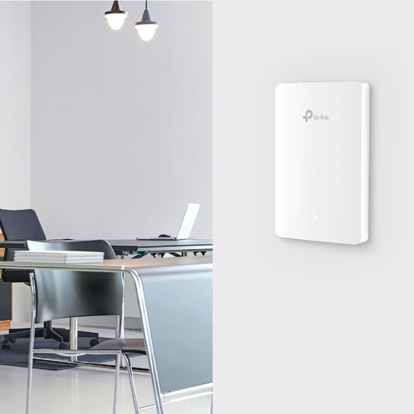 Router TP-Link bianco montato su parete bianca, con scrivania e sedie sullo sfondo.