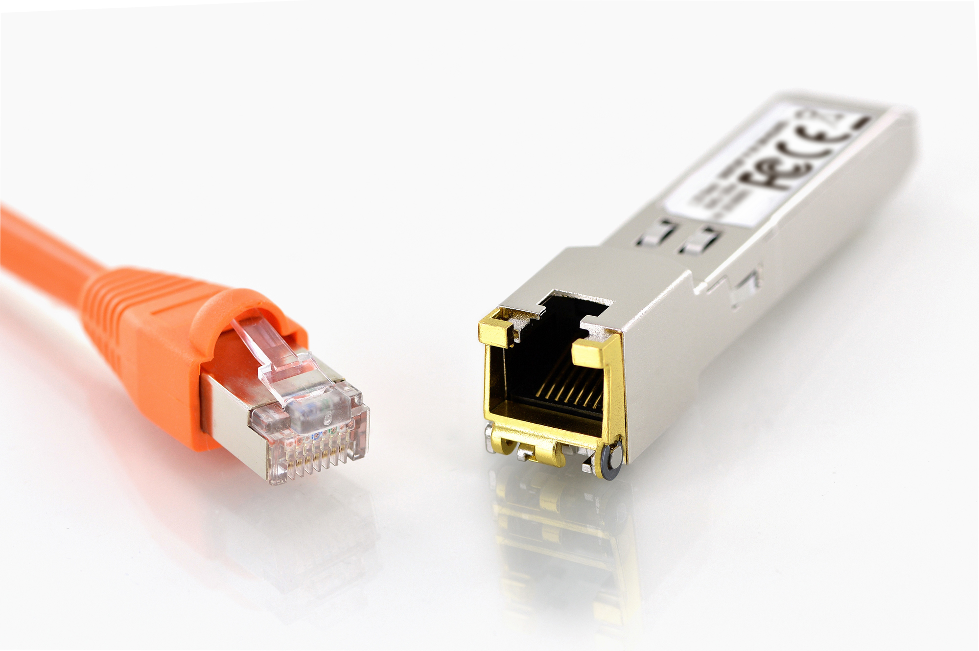 Un cavo Ethernet arancione e un modulo ricetrasmettitore argentato su sfondo bianco.