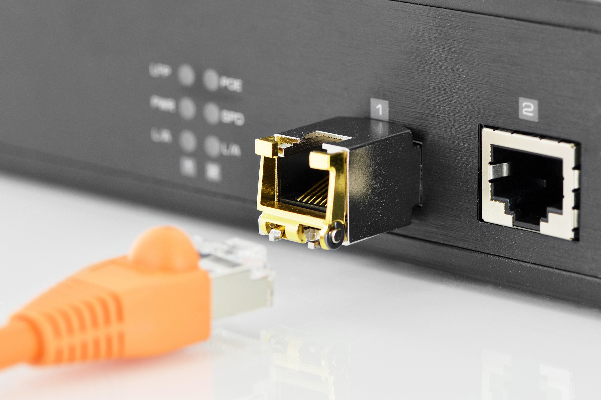 Un cavo Ethernet arancione si avvicina a una porta aperta su un dispositivo di rete nero.