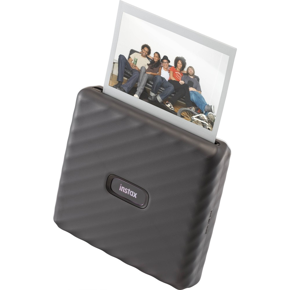 Koyu renkli bir Instax yazıcı, koltukta oturan beş arkadaşın fotoğrafını çıkarıyor.