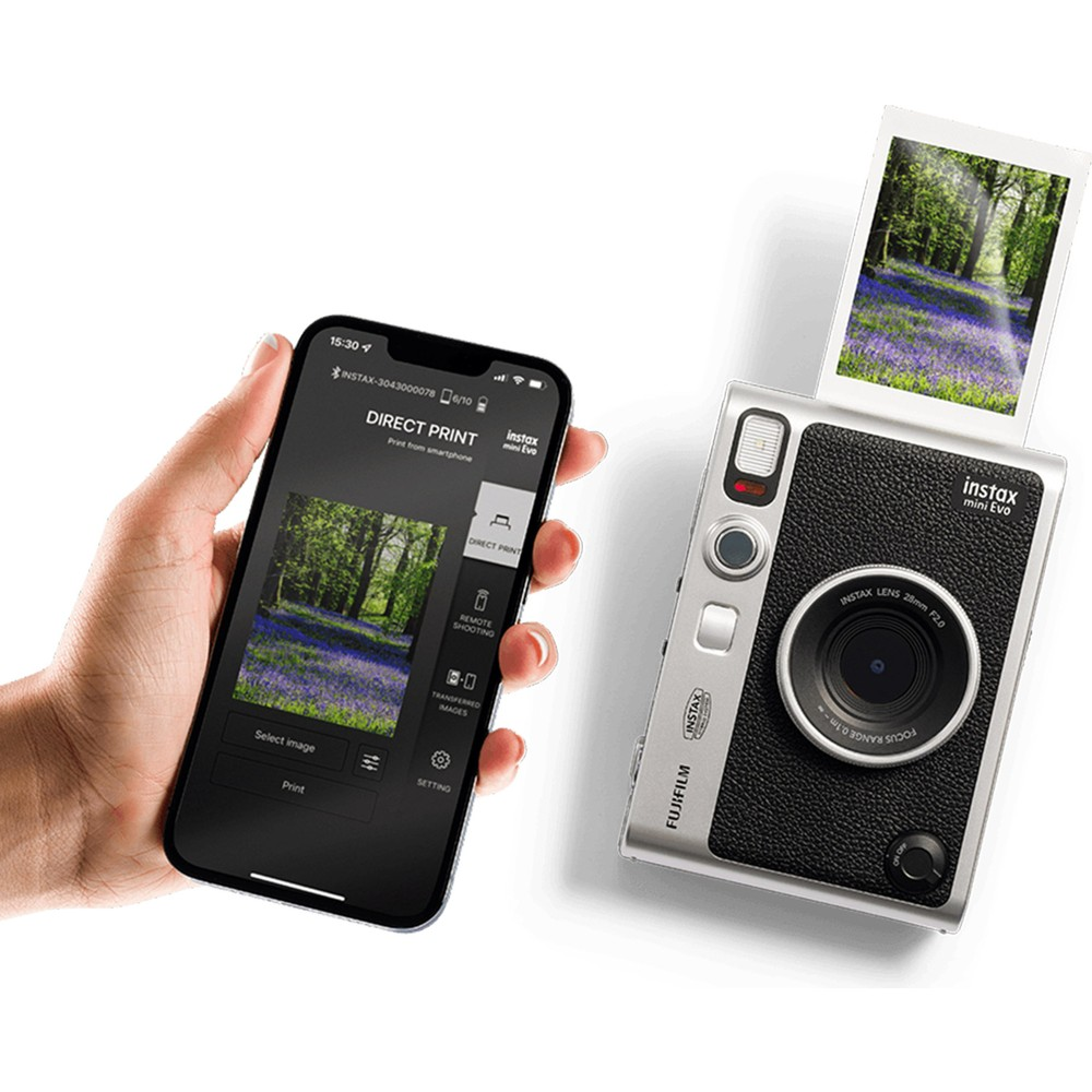 Elinde orman goruntusu olan telefon. Yaninda, ayni goruntuyu Instax kamera basiyor.