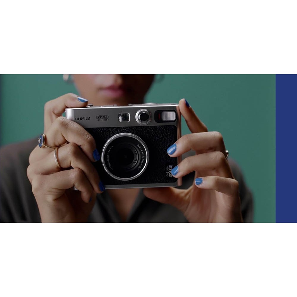 Bir kişi gümüş ve siyah Fujifilm Instax Mini Evo fotoğraf makinesi tutuyor.