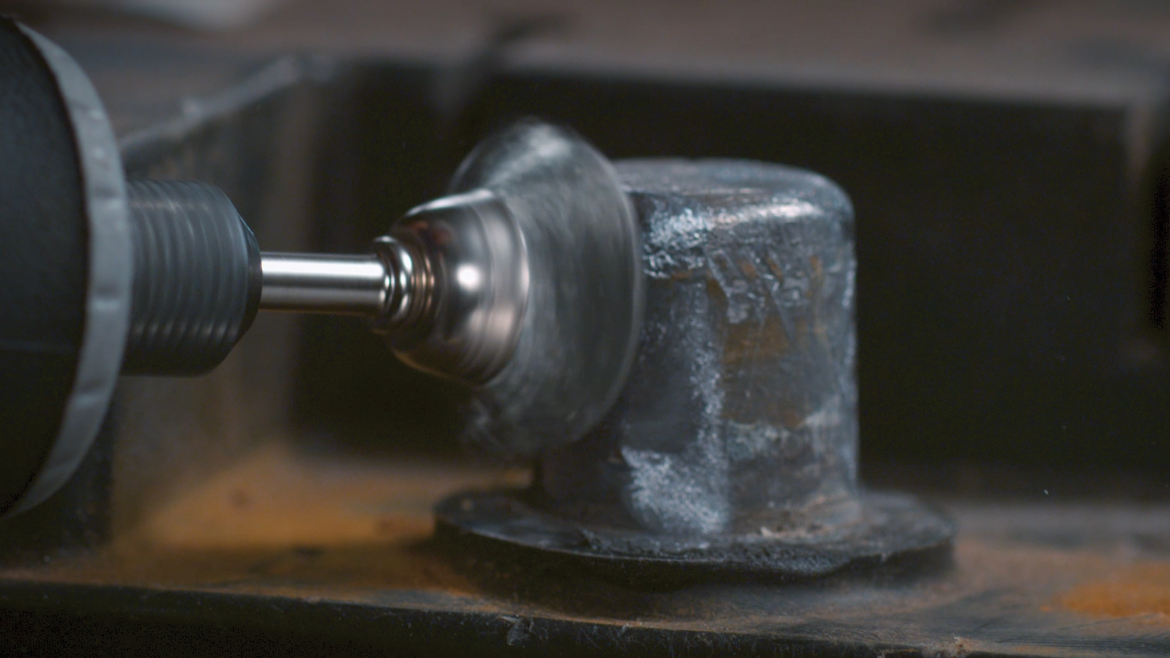 Ein Schleifwerkzeug bearbeitet einen metallischen Bolzen mit einer breiten Basis.