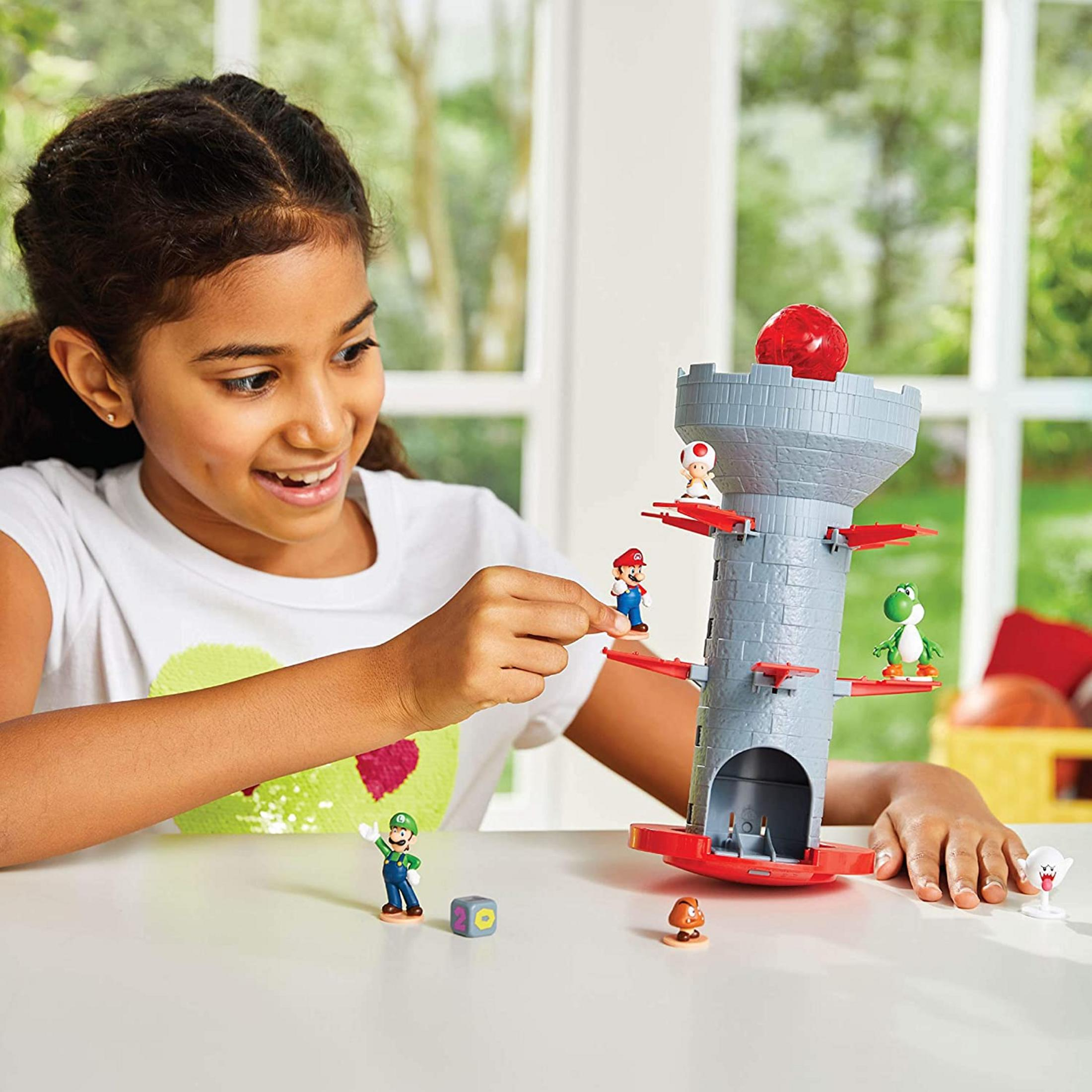 Ein Mädchen spielt mit einem Super Mario-Turmspiel mit Figuren wie Mario, Luigi, Yoshi und Toad.