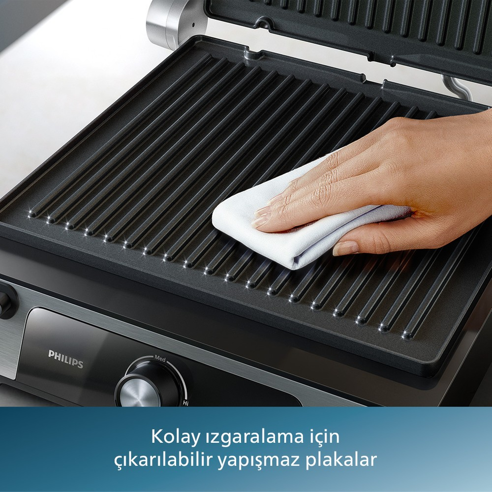 Eine Hand reinigt eine Grillplatte mit einem weißen Tuch.