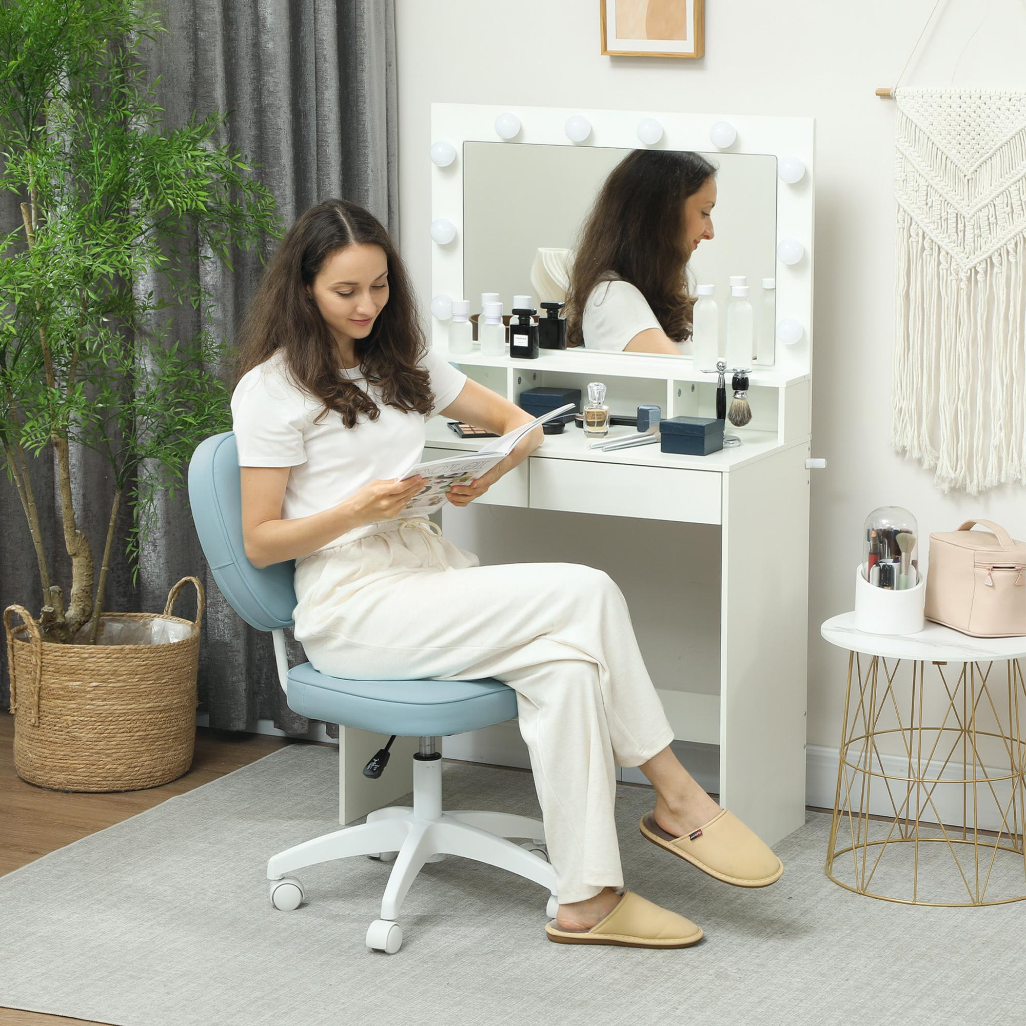 Una mujer lee una revista sentada en una silla de escritorio junto a una mesa de tocador.