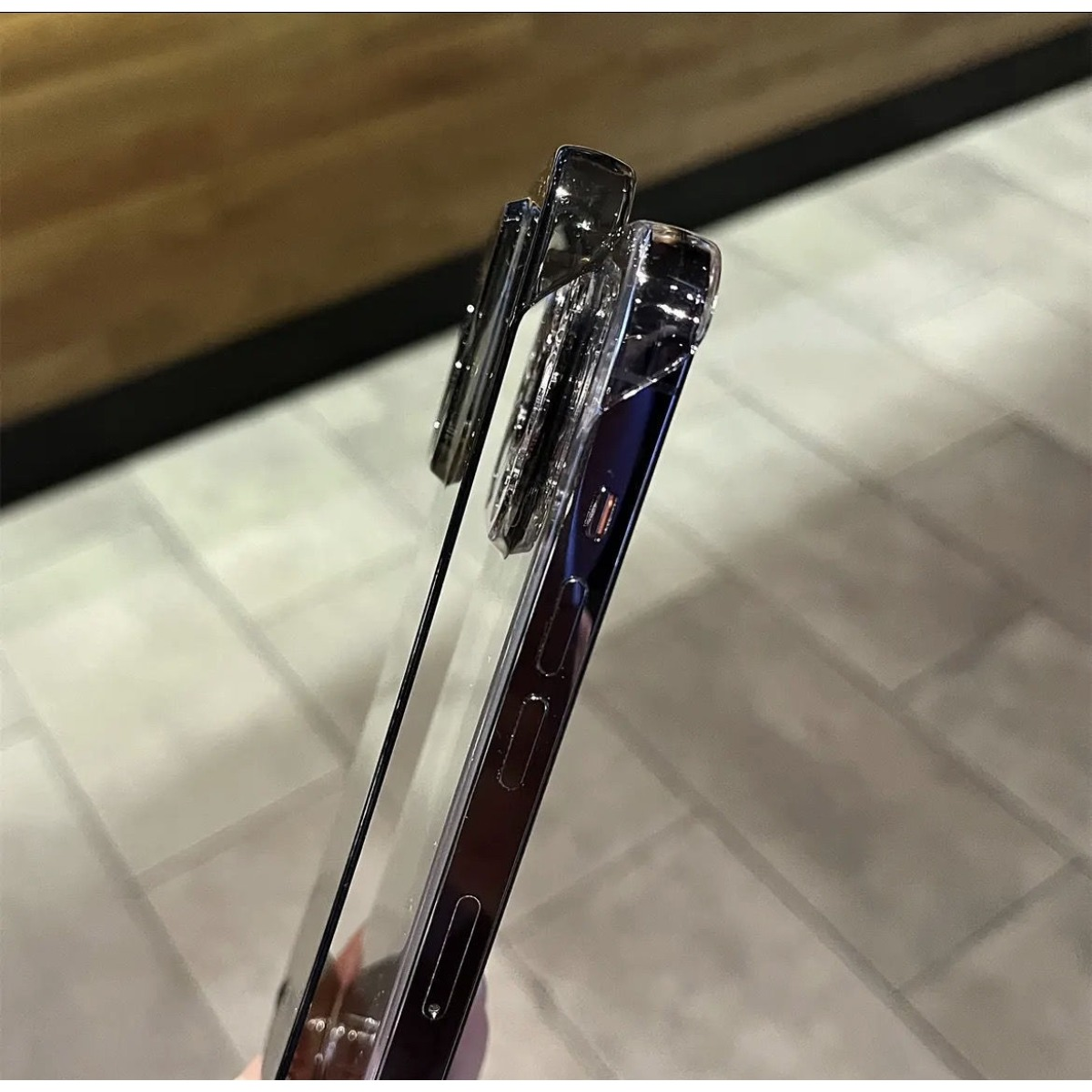 Ein silbernes Handy mit einer transparenten Hülle, das auf einer gemusterten Oberfläche liegt.