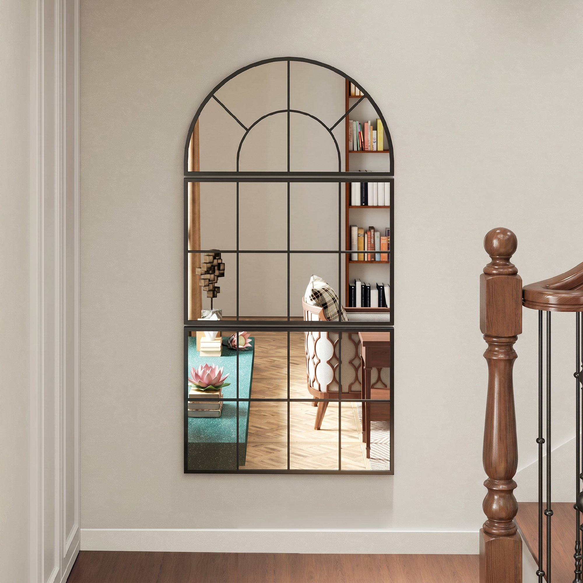Un espejo de ventana arqueado con marco negro refleja una habitación con libros y muebles.