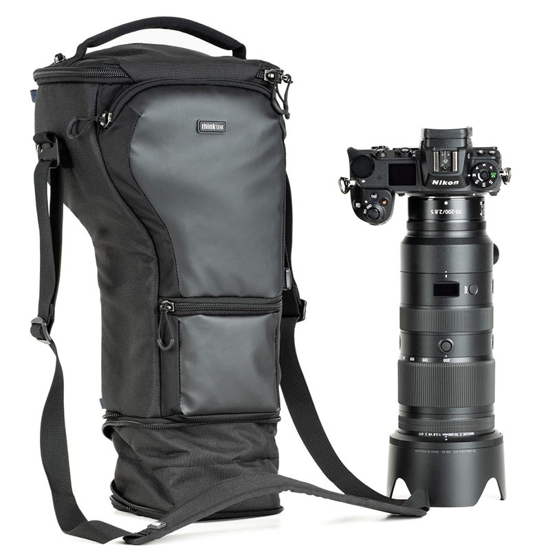Una bolsa de cámara negra y una cámara Nikon con teleobjetivo sobre fondo blanco.