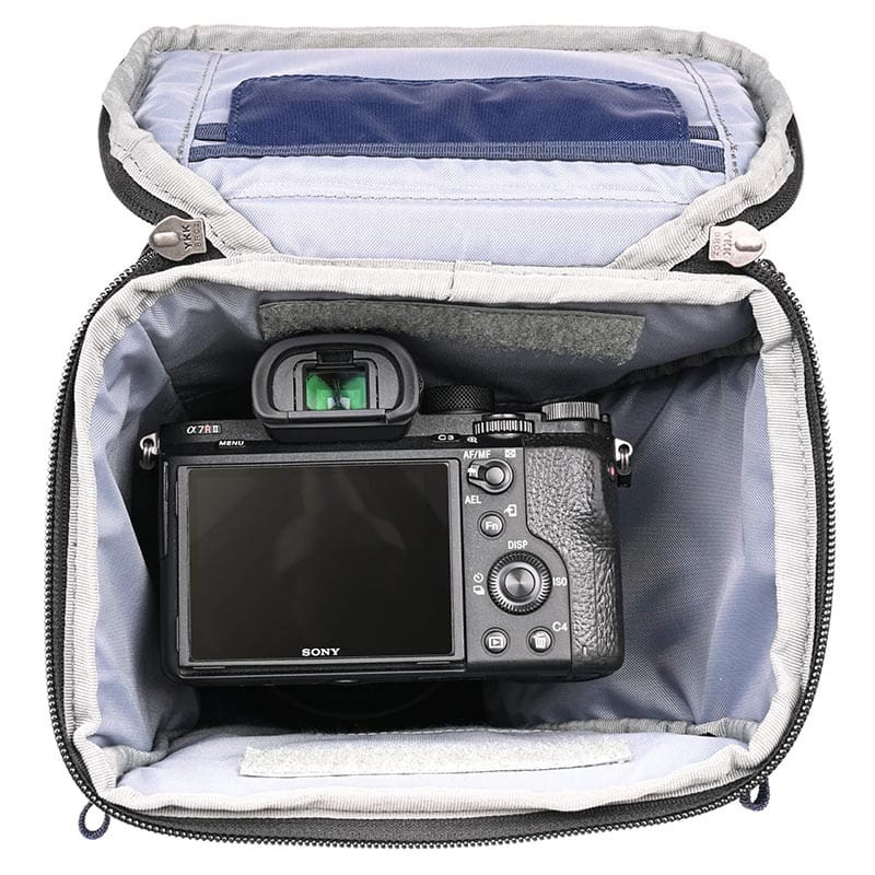 Una cámara Sony Alpha 7R dentro de una bolsa de cámara gris abierta con cremallera negra.