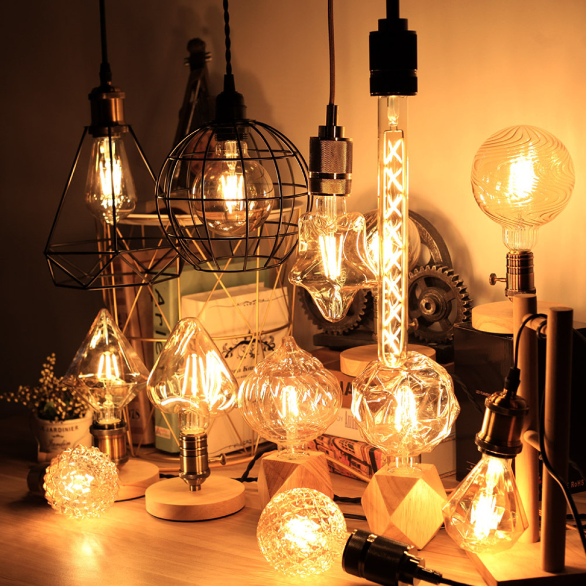 Verschiedene dekorative Edison-Glühbirnen und Lampen mit warmem Licht stehen auf einer Holzoberfläche.