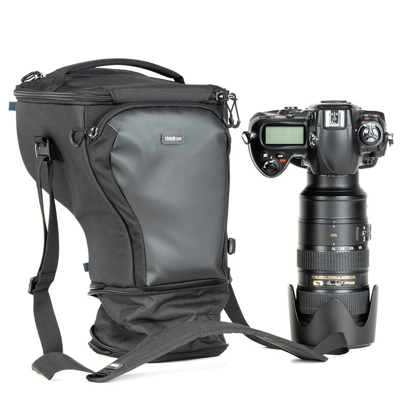 Una bolsa de cámara negra y una cámara DSLR negra con lente sobre fondo blanco.