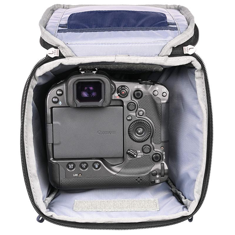 Una cámara digital Canon yace dentro de una bolsa de cámara gris.