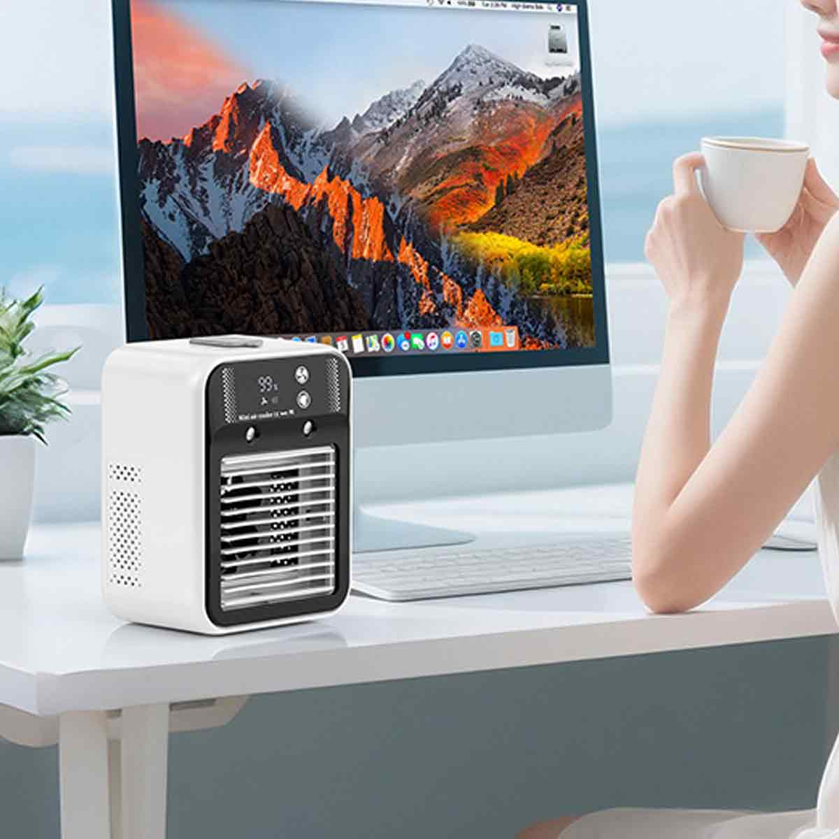 Ein weißer Mini-Luftkühler steht auf einem Schreibtisch vor einem Computermonitor.