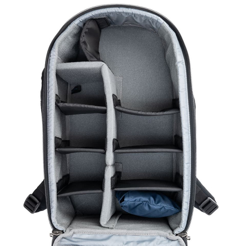 Una mochila negra vacía con divisores acolchados y un cojín azul dentro.