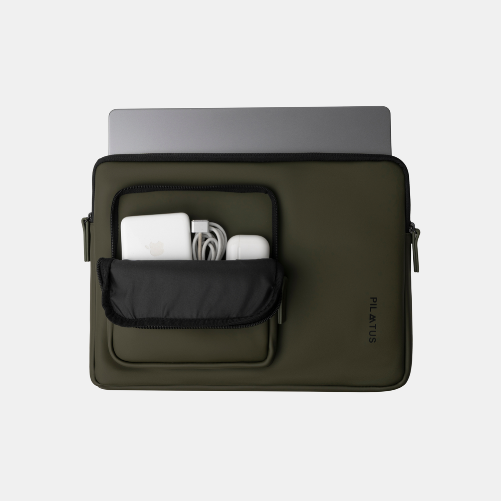 Una custodia per laptop verde scuro con MacBook, caricabatterie e AirPods nella tasca frontale.