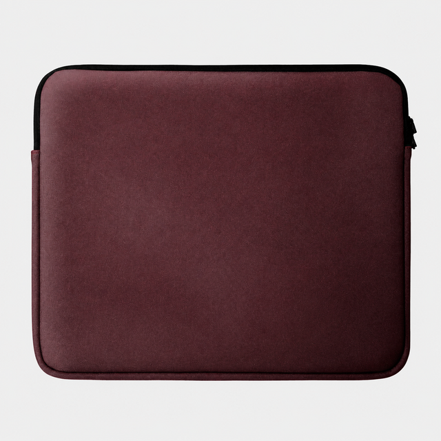Una custodia per laptop rosso scuro con cerniera nera, appoggiata su sfondo grigio.