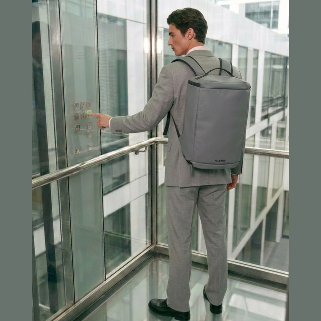 Un uomo in abito preme un pulsante dell'ascensore, con zaino.