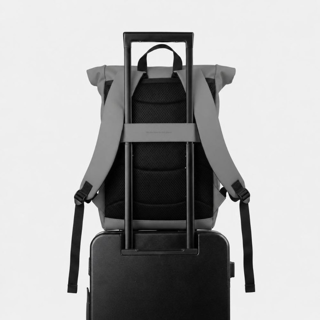 Zaino grigio su trolley nero con manico argentato.