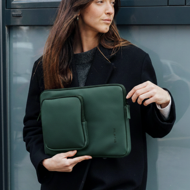 Una donna tiene una borsa per laptop verde scuro con tasca.