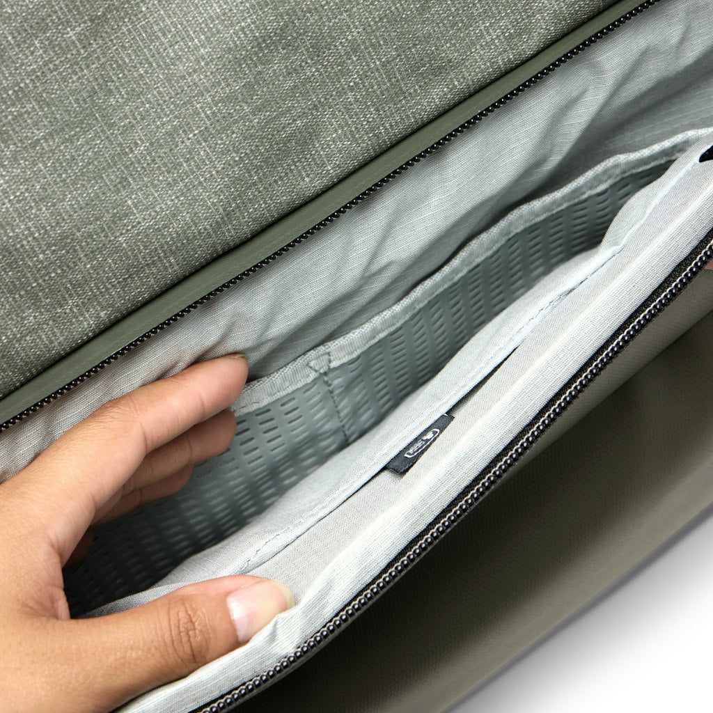Eine Hand greift in ein offenes, hellgraues Fach mit Netzfutter einer Tasche.