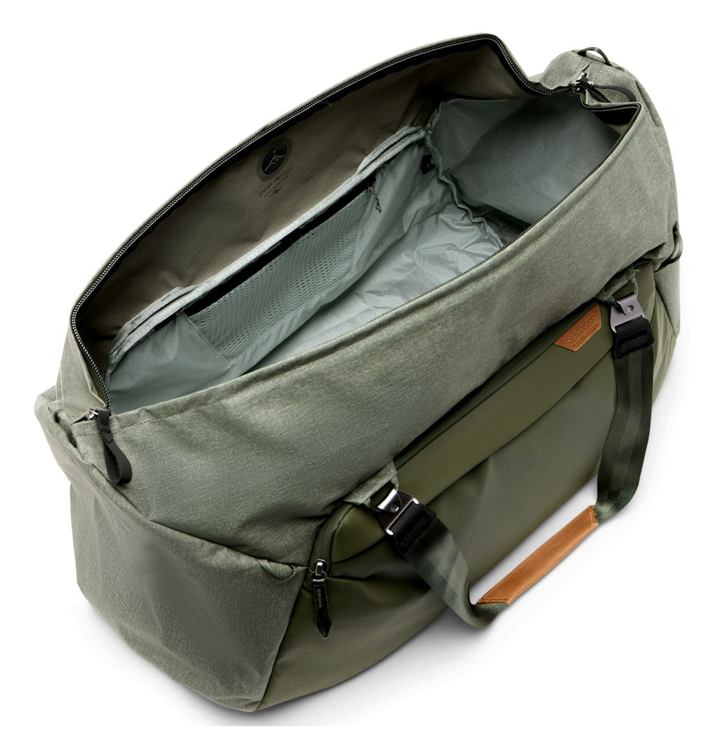 Offene grüne Reisetasche mit internen Netztaschen und Ledergriffdetails.