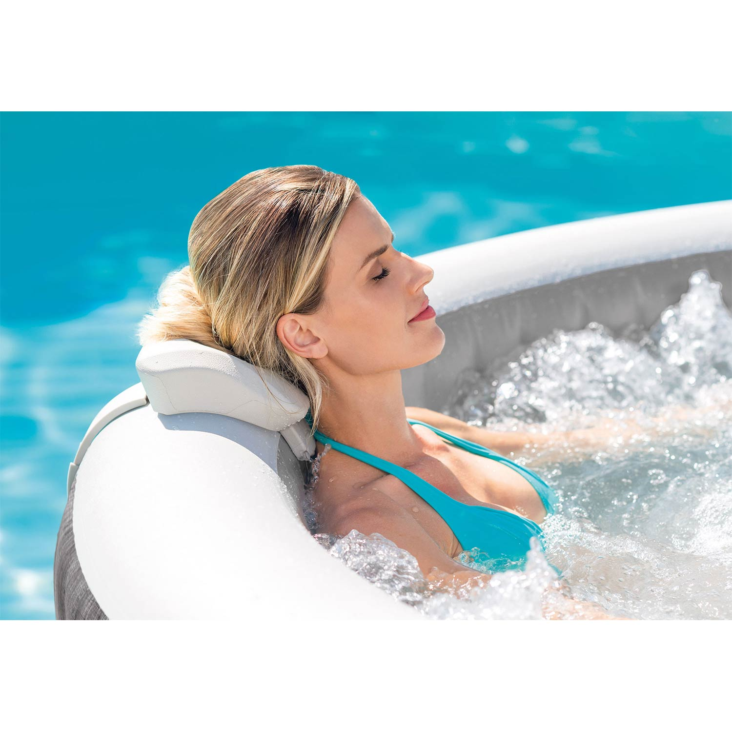 Eine Frau in einem türkisfarbenen Badeanzug entspannt sich in einem Whirlpool mit sprudelndem Wasser.