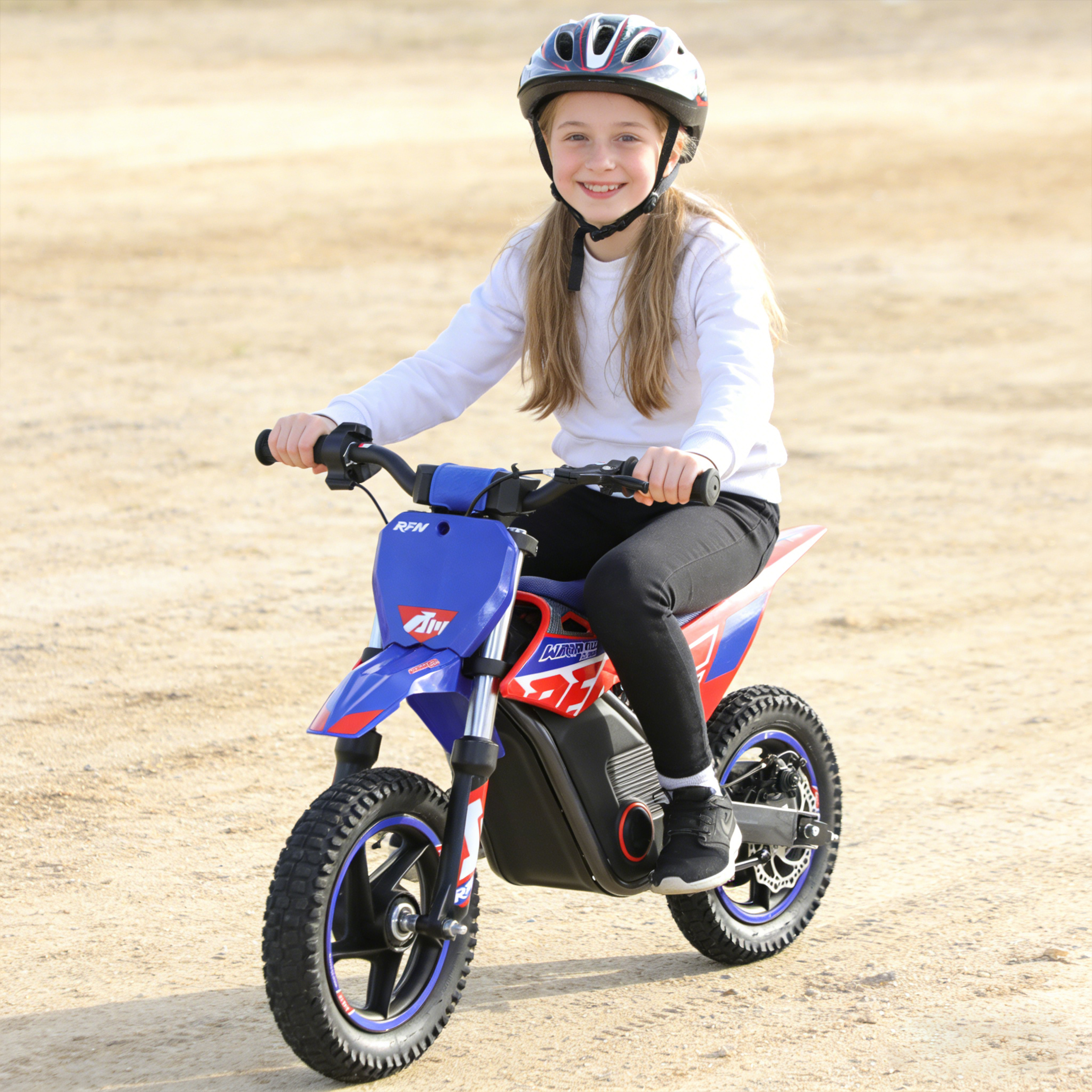 Ein Mädchen mit Helm auf einem blauen Motorrad sitzt auf sandigem Boden.
