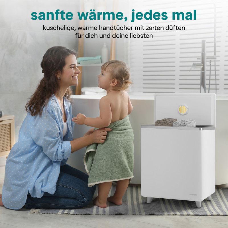 Mutter kniet neben Baby, das in Handtuch gewickelt ist, neben einem Handtuchwärmer.