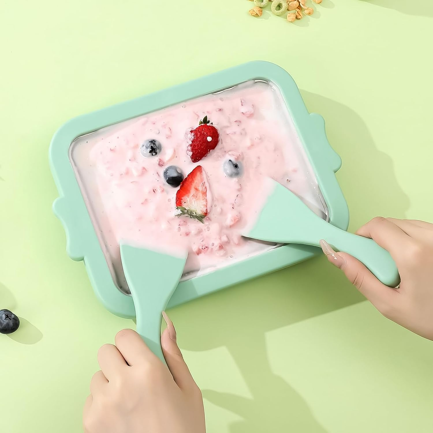 Eis mit Erdbeeren und Blaubeeren wird mit zwei Schabern hergestellt.