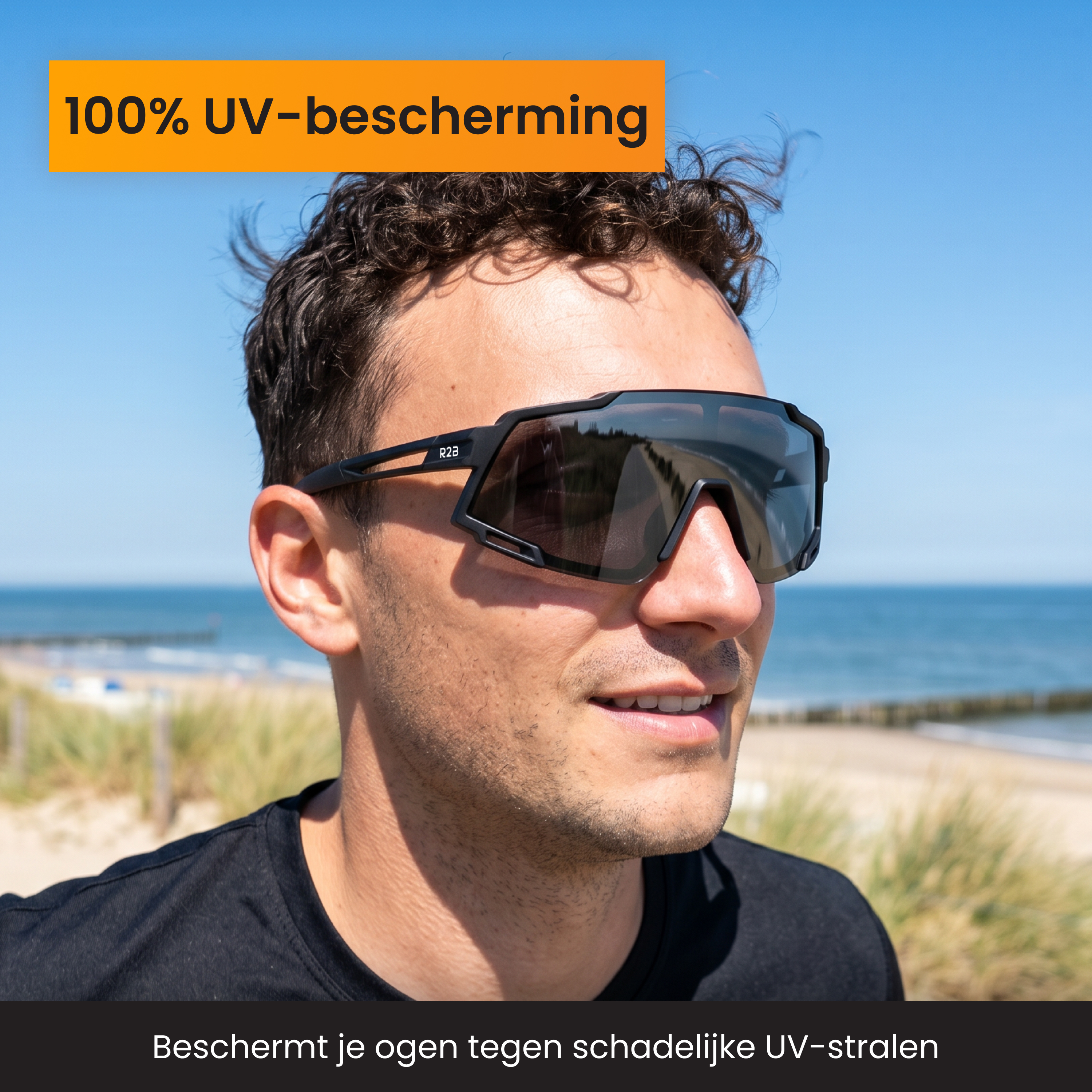 Mann mit dunklem Haar und Sonnenbrille am Strand bei Sonnenschein.