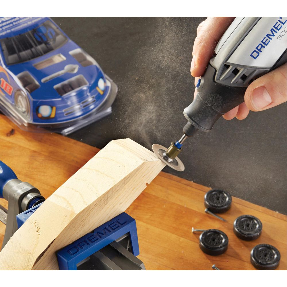 Un Dremel taglia legno con un'auto giocattolo e ruote vicine.
