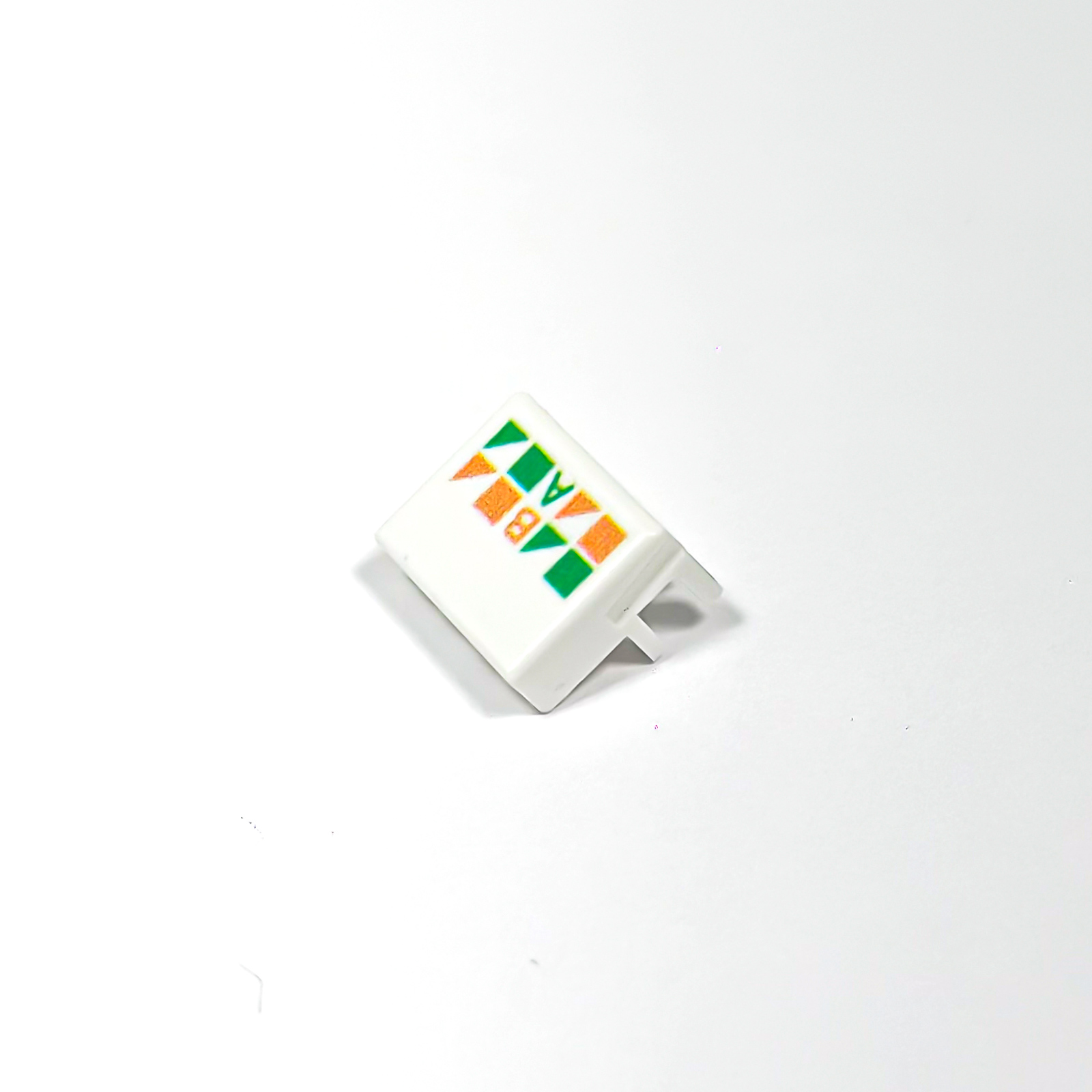 Ein weißes Eckteil mit orange-grünen geometrischen Mustern.