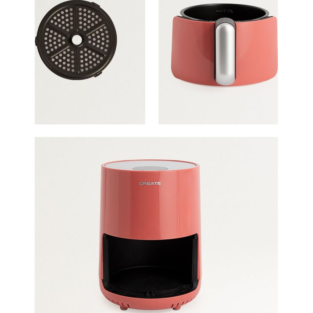 Un air fryer coral con asa plateada y una rejilla perforada.