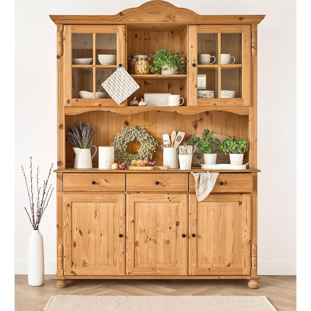 Un buffet en bois avec portes vitrées, rempli de vaisselle, de plantes et de décorations.
