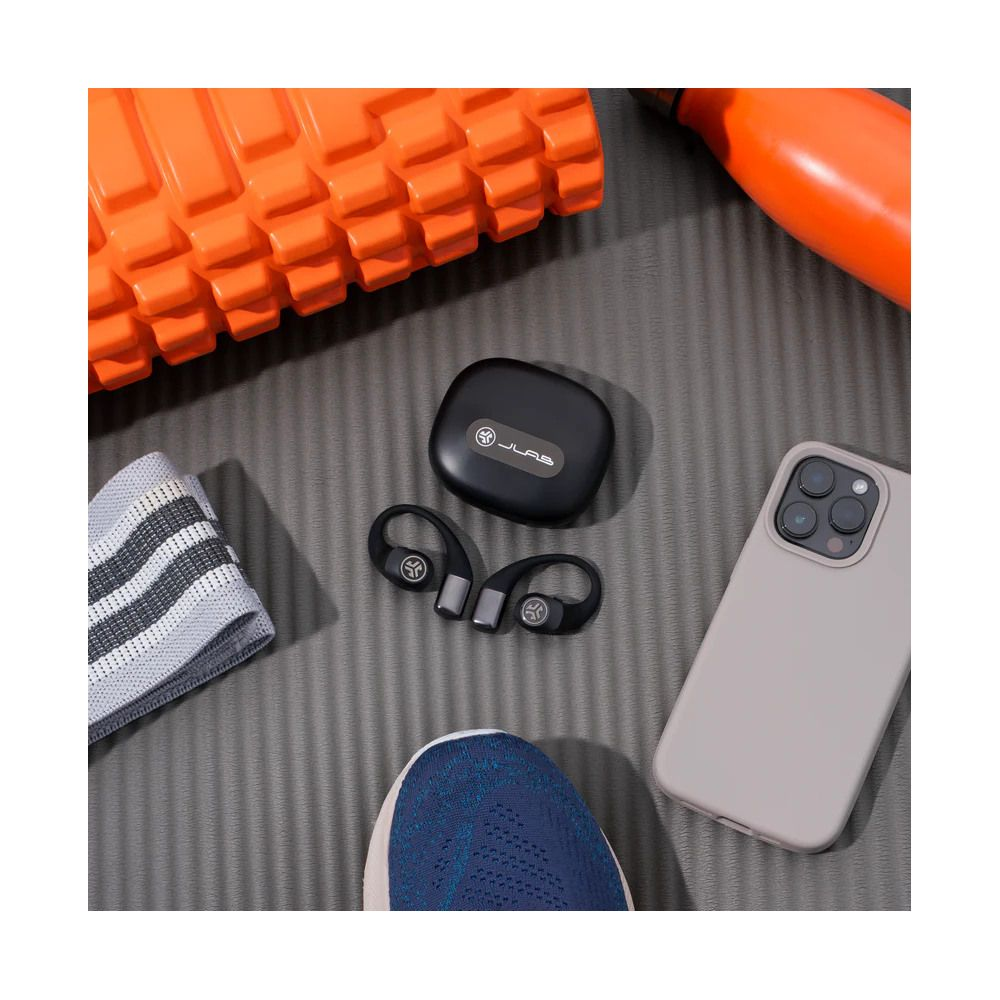 Rullo in schiuma arancione, auricolari, telefono, fascia e scarpa su tappetino.