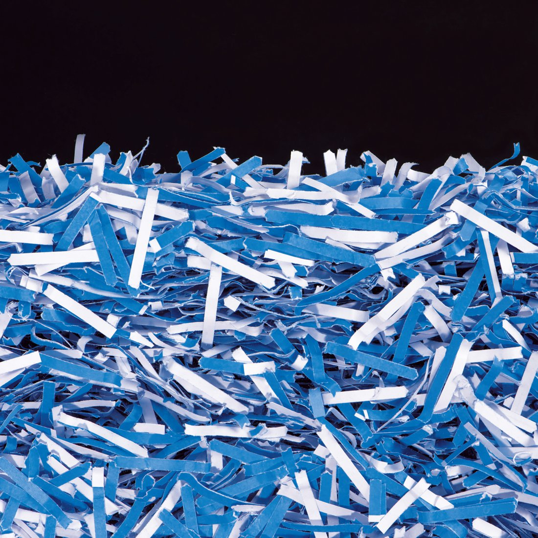 Ein Haufen zerkleinerter weißer und blauer Papierstreifen auf schwarzem Hintergrund.