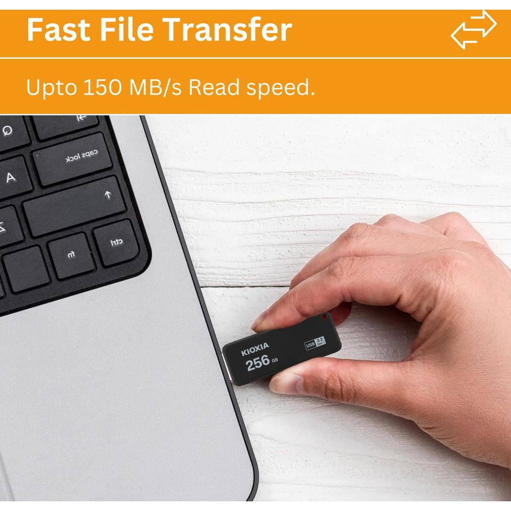 Una mano tiene un'unità flash USB Kioxia da 256 GB accanto a un laptop.