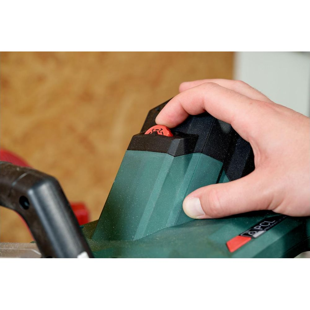 Hand dreht roten Einstellknopf 2-3 an einem grünen Elektrowerkzeug.