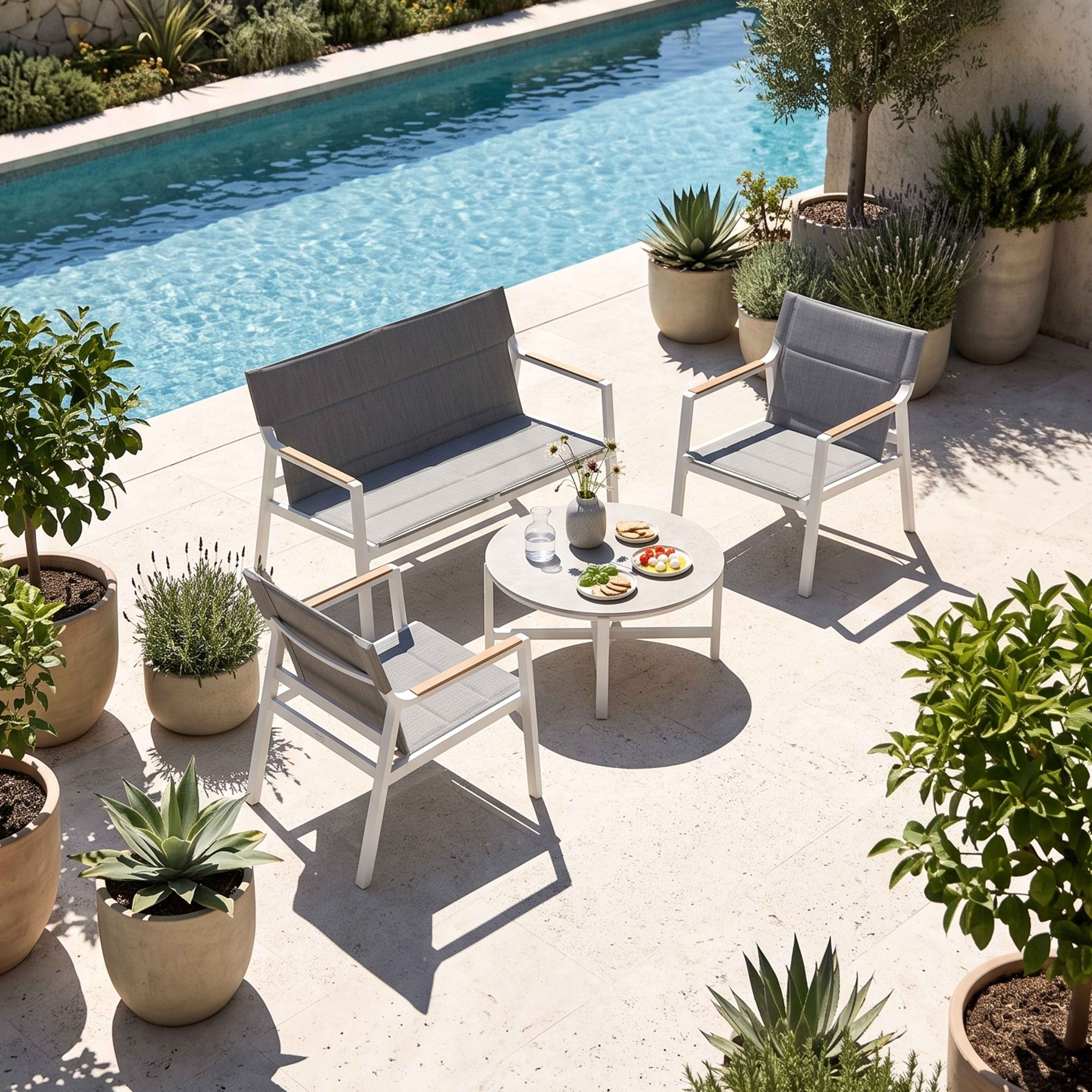 Gartenmöbel am Pool: Sofa, Sessel, Tisch mit Snacks, umgeben von Pflanzen.