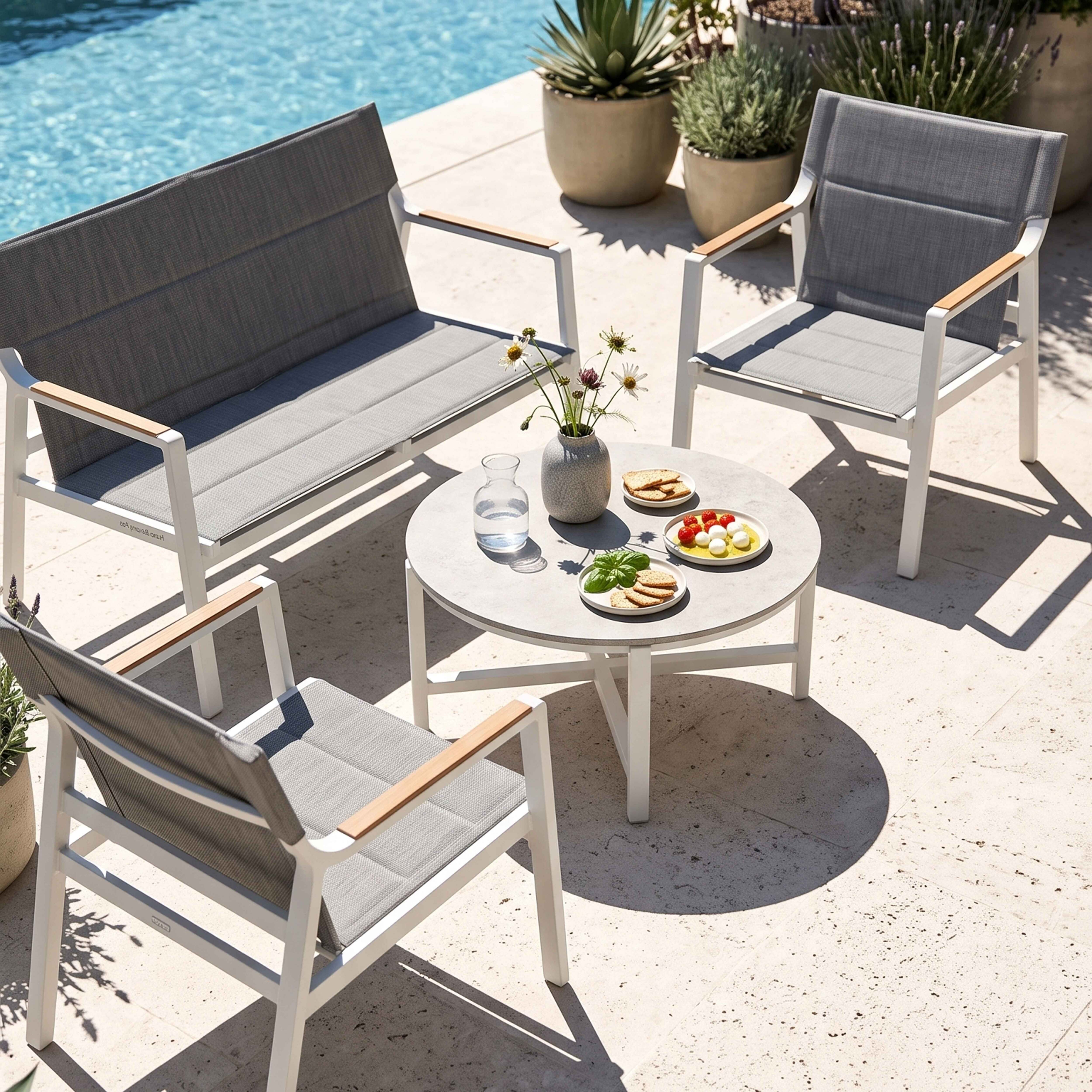 Graue Gartenmöbel am Pool mit Tisch und Snacks.