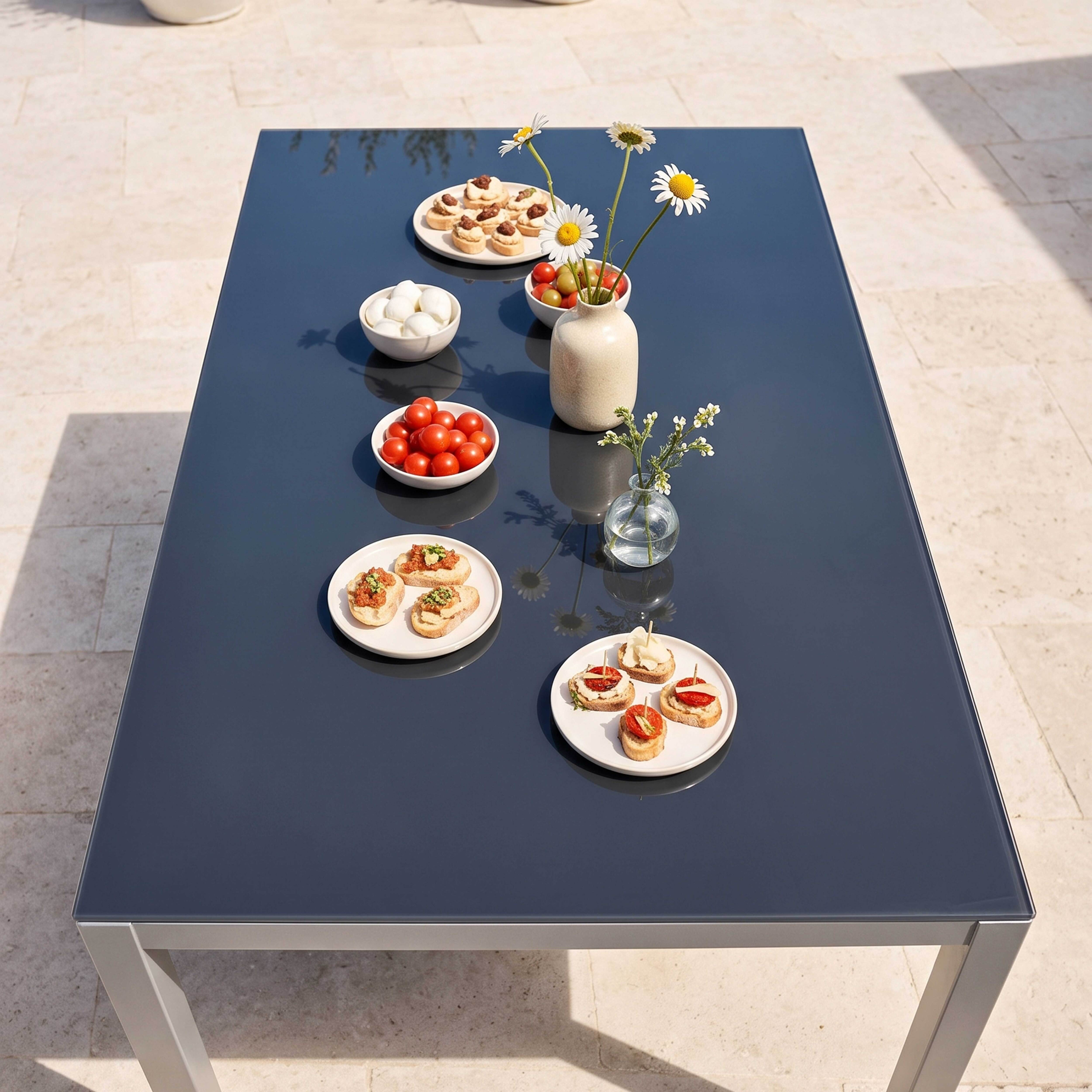 Ein dunkelgrauer Tisch mit Snacks und Blumen im Freien.