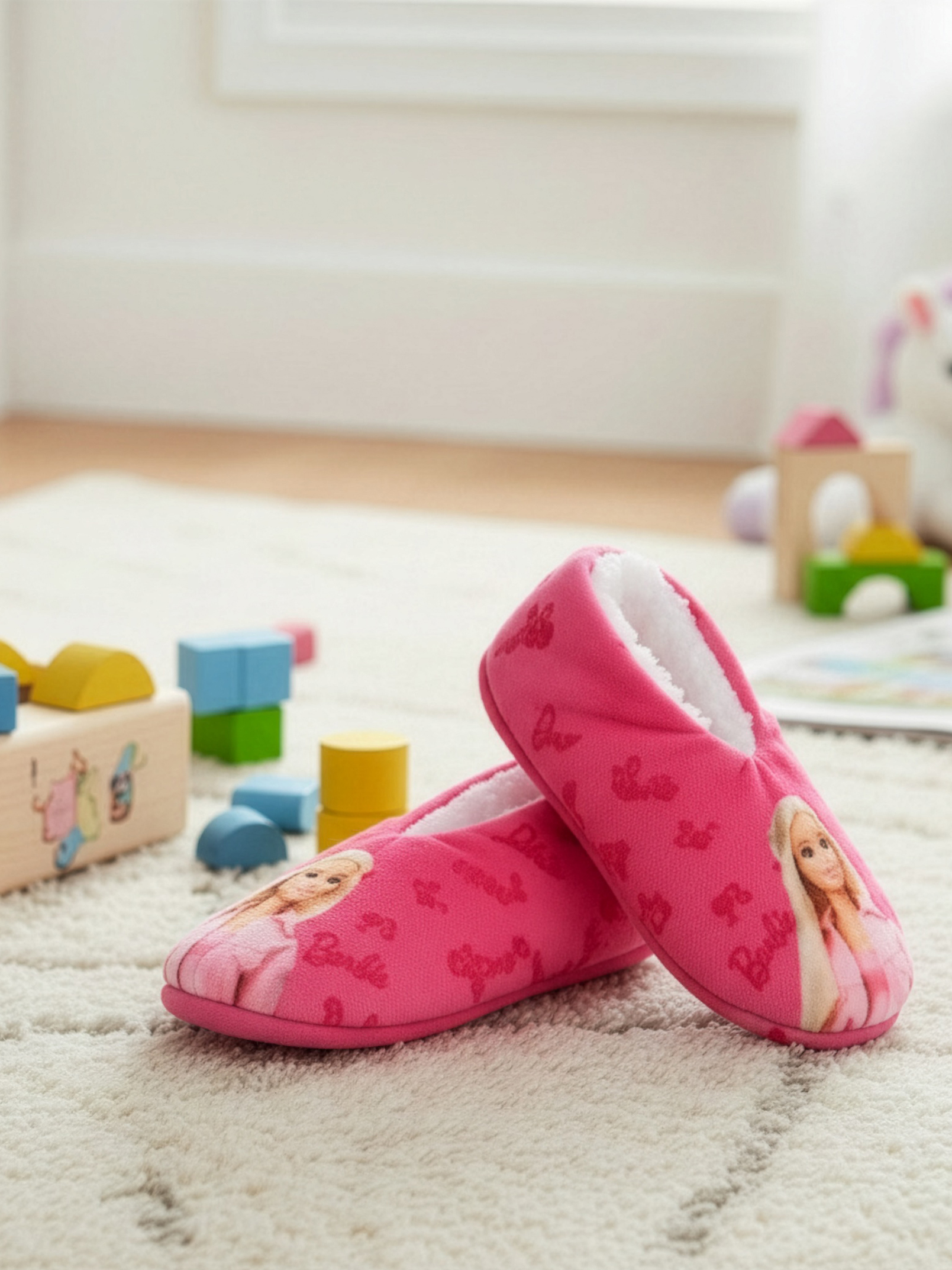 Zwei pinke Barbie-Hausschuhe mit weißem Futter liegen auf einem Teppich.