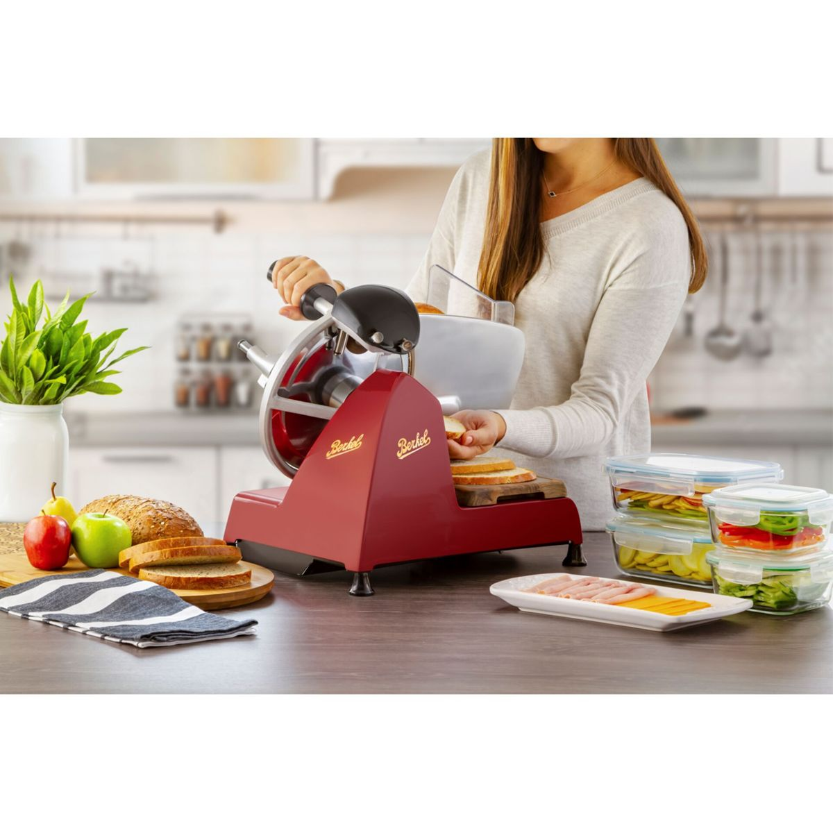 Una donna affetta pane con un'affettatrice rossa in cucina.