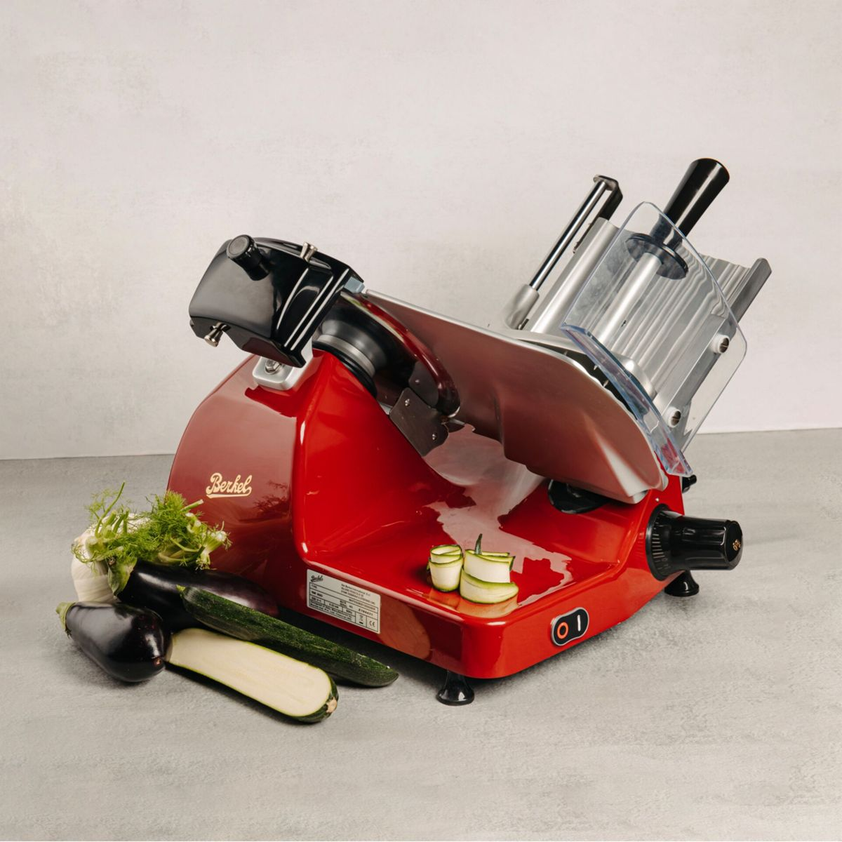 Una affettatrice Berkel rossa con verdure: melanzana, zucchine ed erbe aromatiche.