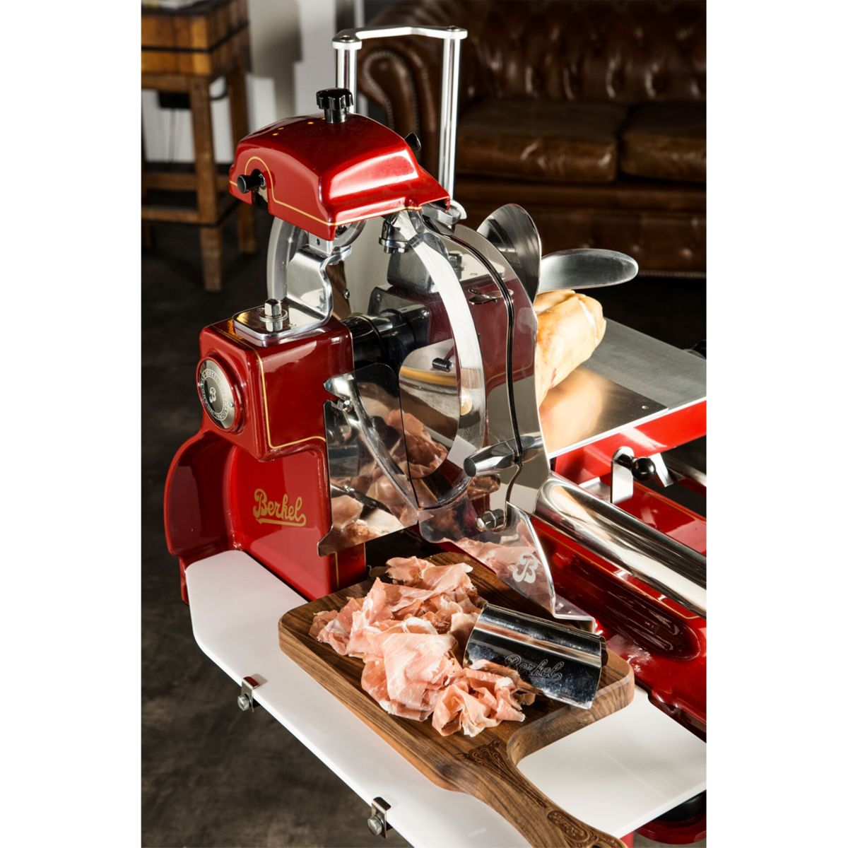 Una affettatrice Berkel rossa con carne affettata su tagliere in legno.