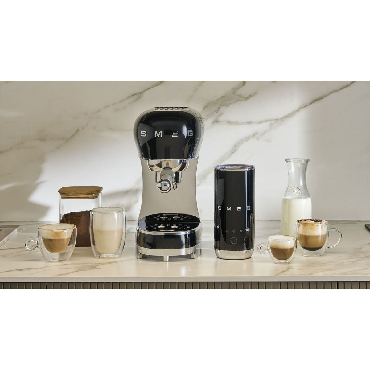 Espresso makinesi, süt köpürtücü, kahve bardakları ve süt sürahisi mermer üzerinde.