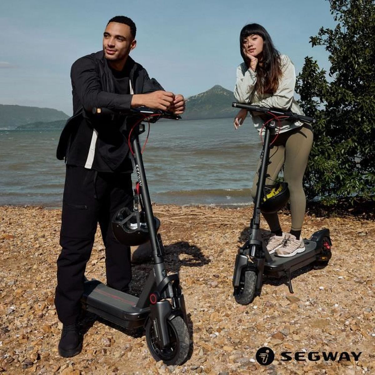 Un uomo e una donna stanno con scooter elettrici su una spiaggia.